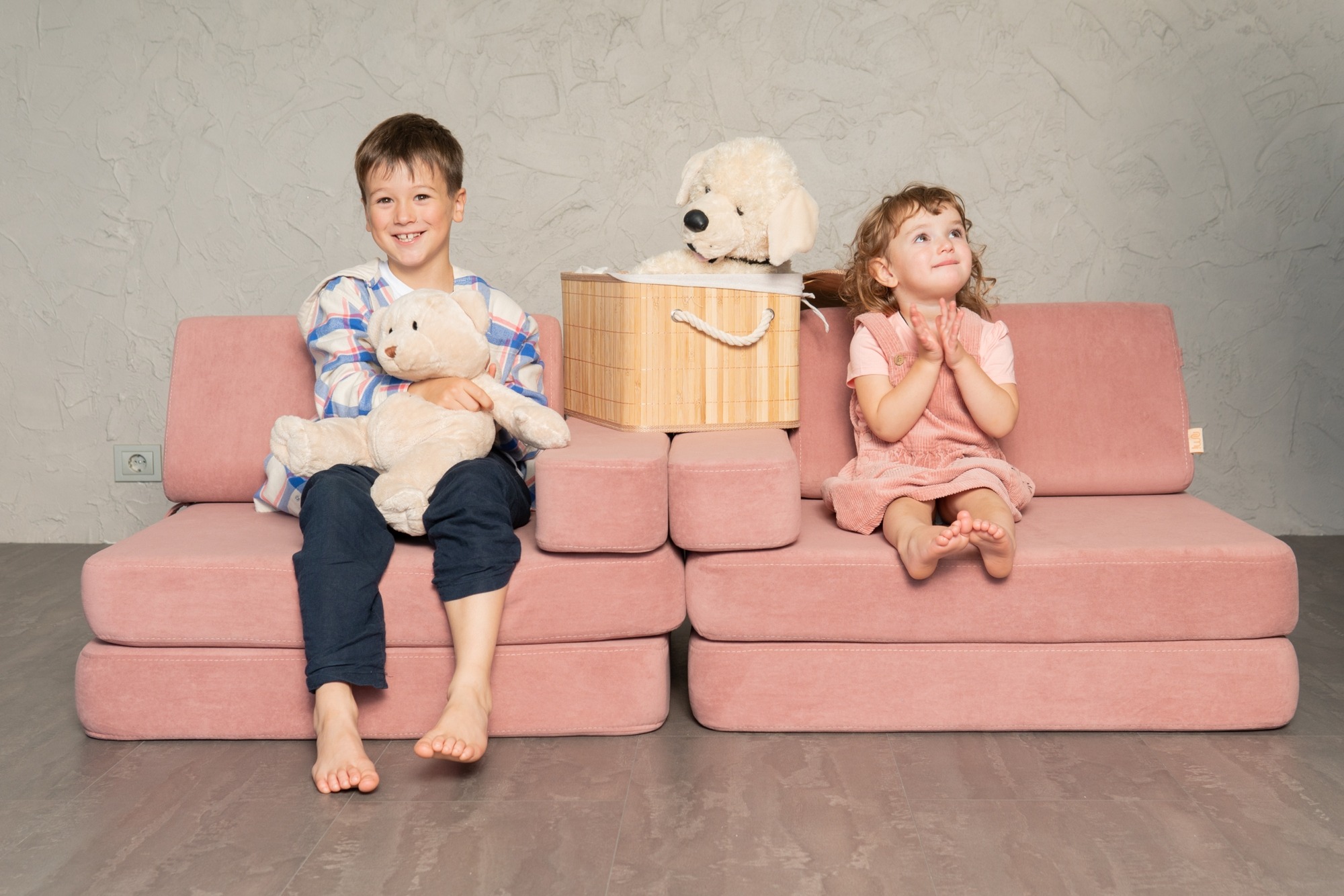 Poiss ja tüdruk istuvad roosa NUMI-sangari diivanil.