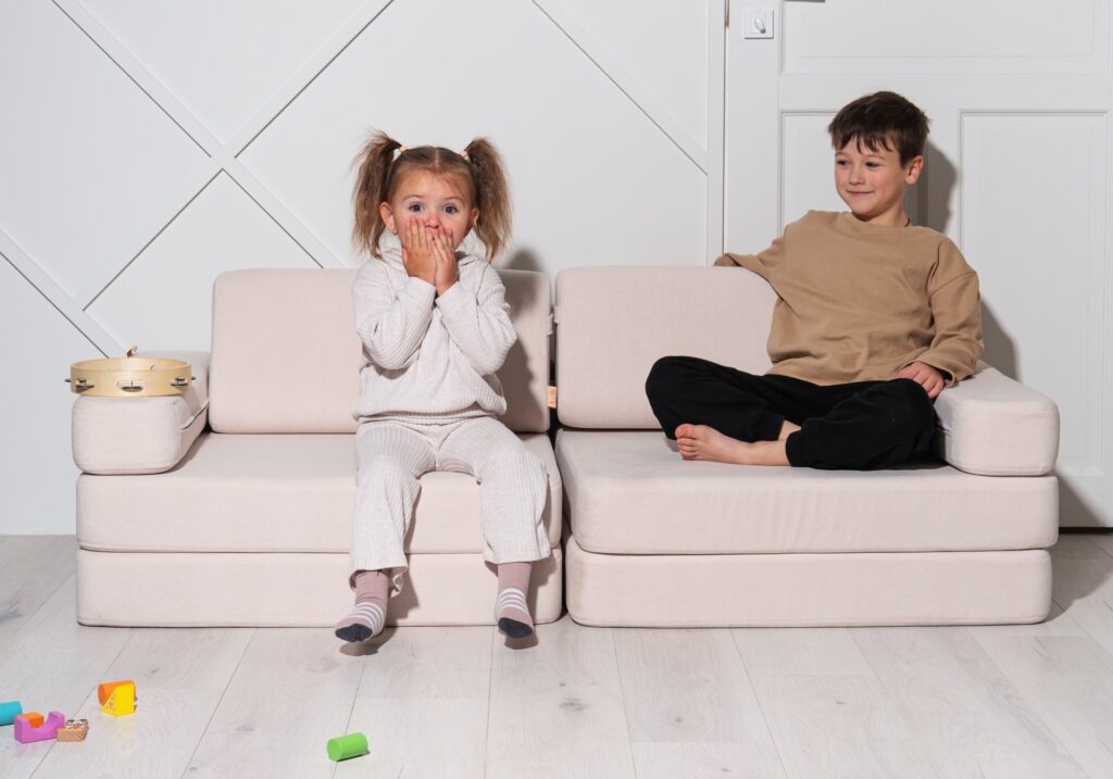 A girl and a boy are sitting on a white NUMI hero sofa